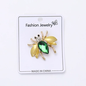 Detail of honey bee brooch with green gemstone on Fashion Jewelry display card