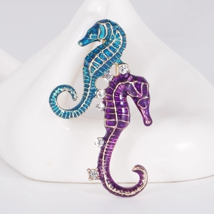 Detailed view of seahorse brooches with blue and purple enamel on a swan base