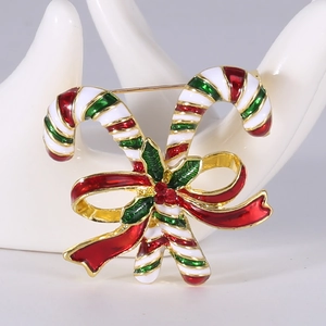 Detail of Christmas candy cane brooch with colorful enamel and green holly leaf accents
