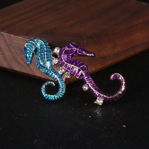 Macro detail of blue and purple enamel seahorse brooches with sparkling rhinestones
