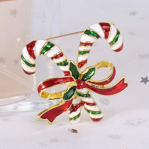 Detailed close-up of Christmas candy cane brooch with red bow and holly on mesh fabric