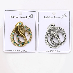 Dettaglio di spille a cobra con texture a squame e cristalli in oro e argento