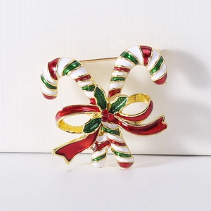 Detail view of gold alloy candy cane brooch with red enamel bow and green holly leaves