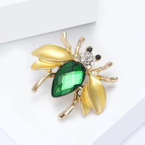 Elegant gold bee brooch featuring a large green faceted gemstone and sparkling rhinestones