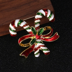 Macro detail of Christmas candy cane brooch with red enamel bow and holly leaf accents