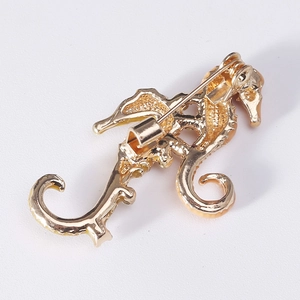 Back view of gold seahorse brooch with pin mechanism and textured metal surface