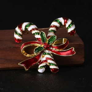 Close-up of Christmas candy cane brooch with red bow and holly leaves on wooden base