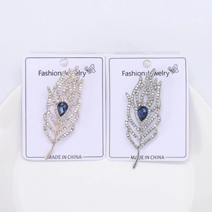 Detailed macro view of rose gold and silver feather brooches with blue teardrop stones
