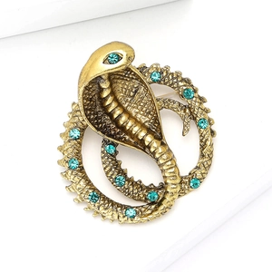 Spilla cobra in oro vintage con strass blu e scaglie testurizzate su sfondo bianco