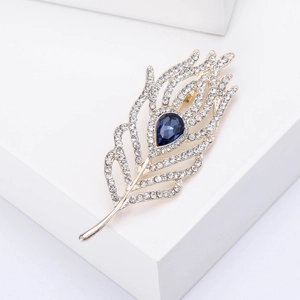 Detailed view of elegant feather brooch with blue pear-shaped gemstone and white rhinestones