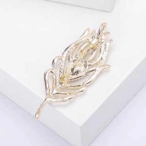 Detailed close-up of the golden feather brooch back with secure pin clasp and metal texture
