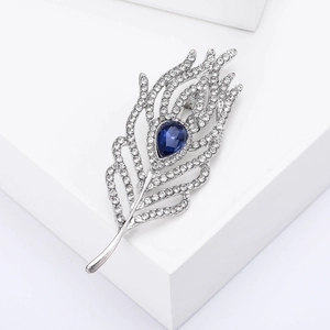 Macro detail of silver feather brooch with blue teardrop gemstone and white crystals