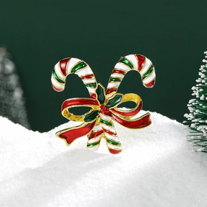 Christmas candy cane brooch with red bow and green leaves on snowy holiday background