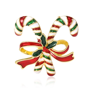 Christmas candy cane brooch with red bow and holly leaf on a reflective white surface