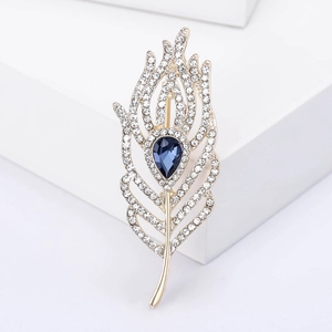 Elegant gold feather brooch with blue teardrop gemstone and sparkling white rhinestones