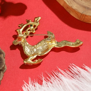 Vue arrière de la broche renne doré avec fermoir sur un fond festif de Noël