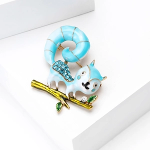 Detail shot of light blue enamel squirrel brooch with rhinestones on golden branch