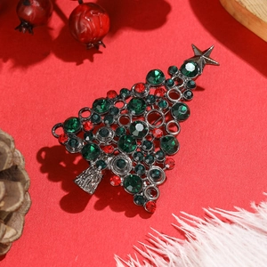 Silver Christmas tree brooch with red and green rhinestones on festive red background
