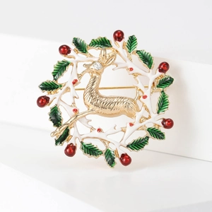 Detailaufnahme der Weihnachtsbrosche mit Rentier-Kranz, Emaille-Blättern und roten Perlen