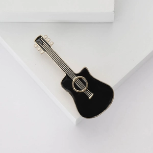 Creative enamel guitar brooch in black and gold alloy finish on minimalist white stairs