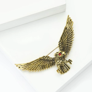 Detail of vintage eagle brooch with antique gold feathers and a striking red gem eye