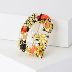 Vintage gold G-letter brooch with pearls and colorful gemstones on minimalist stand