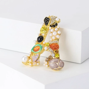 Vintage gold letter A brooch with pearls and colorful crystals on a white display