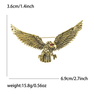 Vintage gold eagle brooch with red eyes, wings spread wide, measuring 6.9cm across