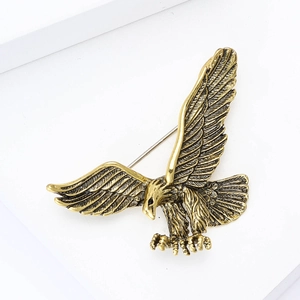 Dettaglio macro della spilla aquila vintage in oro antico con trama metallica e piume