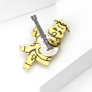 Makroaufnahme der kreativen Kuh-Gitarren-Brosche mit goldener Metallstruktur im Vintage-Stil