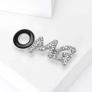 Detail view of OMG brooch with black enamel O and rhinestone-studded M and G letters
