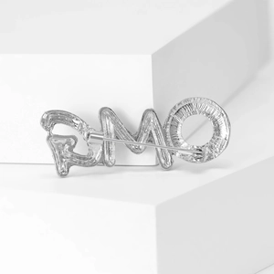 Silver OMG letter brooch with textured finish shown on minimalist white stone background
