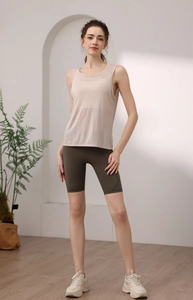 Loose pink yoga vest and dark green cycling shorts worn by model in a minimalist studio