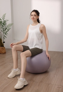 Canotta yoga bianca ampia abbinata a pantaloncini sportivi a vita alta verde oliva su palla