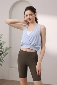 Detail of light blue sleeveless yoga top with V-neck cross design and olive green shorts