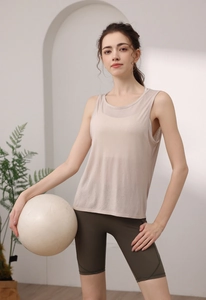 Detail of loose fit yoga tank top for women in soft pink paired with olive cycling shorts