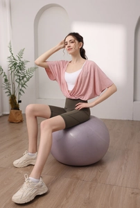 Detail of pink batwing sleeve yoga top and green high waist shorts set on a gym ball