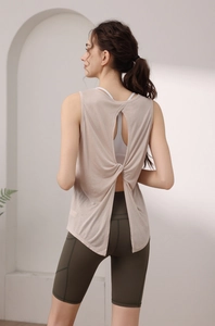 Back view of beige yoga tank top featuring hollow twist detail and green shorts