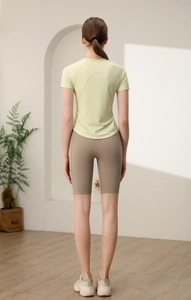 Vista posteriore della maglietta da yoga gialla e pantaloncini sportivi kaki a vita alta