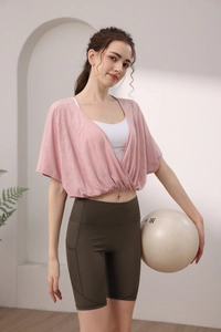 Detailed view of women's pink batwing sleeve yoga top with green high waist sports shorts