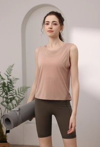 Side view of backless pink yoga top with olive green biker shorts and yoga mat