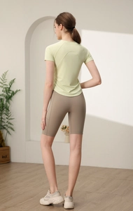 Dettaglio del top da yoga verde chiaro e pantaloncini da ciclista marroni con tasche laterali