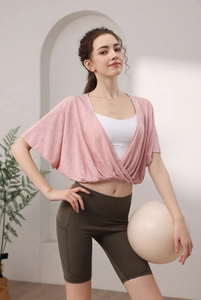 Detail of pink wrap yoga top with high-waist olive biker shorts and side pockets