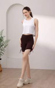Détail du débardeur de sport blanc et du short de yoga marron foncé à cordon latéral