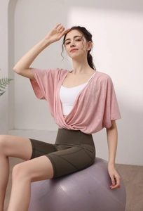Detail of pink wrap-front batwing sleeve sports top and high-waist cycling shorts