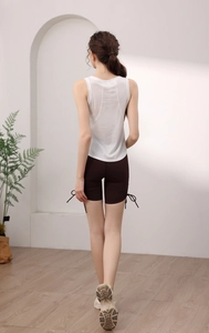 Dettaglio di un top sportivo bianco e pantaloncini da palestra marroni con coulisse su modella
