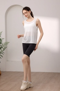 Relaxed fit white yoga vest with black cycling shorts on model in bright indoor setting