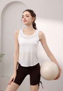Dettaglio del top sportivo bianco smanicato e pantaloncini da yoga marroni con coulisse