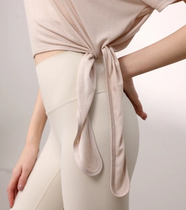 Détail du t-shirt de yoga rose avec nœuds de serrage à la taille et texture de tissu doux