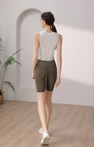 Rear view of tight white tencel yoga tank top and green high-waisted gym shorts